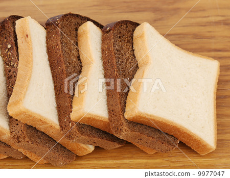 White and brown loaf of bread on wooden table. White and brown loaf of bread on wooden table. 9977047
