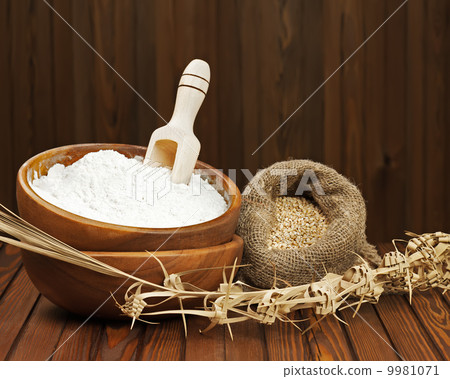 Flour in wooden bowl and wheat in burlap bag. 9981071