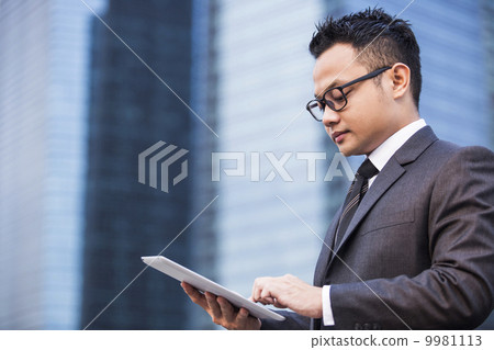 Young male malay executive using a tablet Young male malay executive using a tablet 9981113