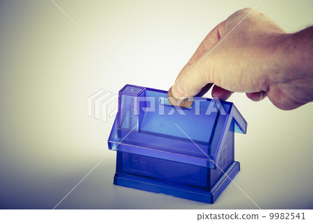 Blue House Money Box with man hand and coin on White Background 9982541