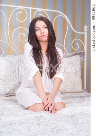 Portrait of brunette woman on the bed. 9991666