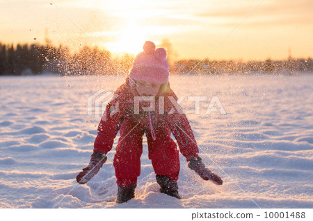 Child enjoying the falling snow in the sun 10001488