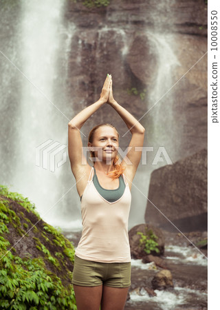 Young woman practicing yoga by the waterfall Young woman practicing yoga by the waterfall 10008550