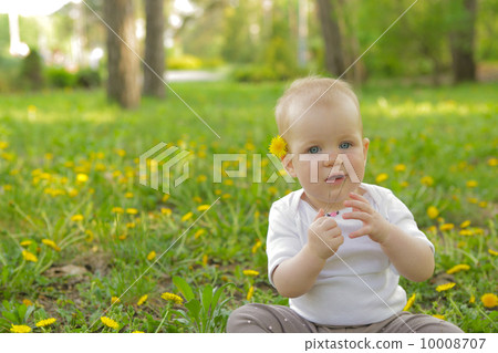 young adorable cheerful baby sit in park on green grass and play 10008707