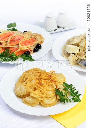 White table with food of meat, salmon rolls and dumplings. 10021596
