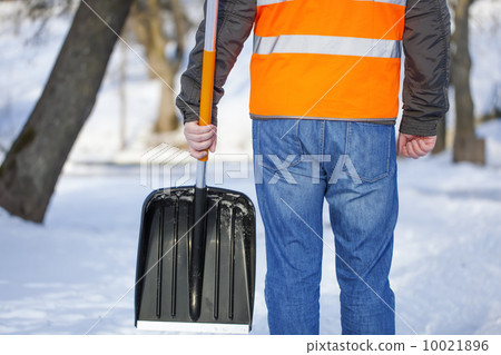 Man with a snow shovel on the sidewalk in winter 10021896