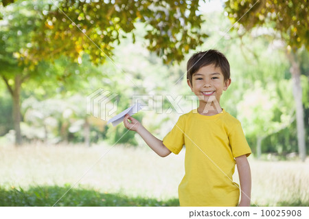 Happy boy playing with a paper plane at park Happy boy playing with a paper plane at park 10025908