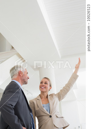 Smiling estate agent showing ceiling to potential buyer Smiling estate agent showing ceiling to potential buyer 10026523