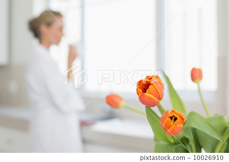 Woman looking out window with focus on tulips Woman looking out window with focus on tulips 10026910