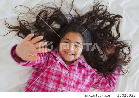 High angle portrait of smiling girl lying in bed High angle portrait of smiling girl lying in bed 10026922