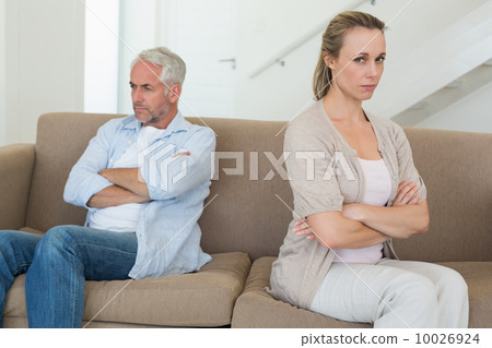 Angry couple sitting on couch not talking to each other Angry couple sitting on couch not talking to each other 10026924