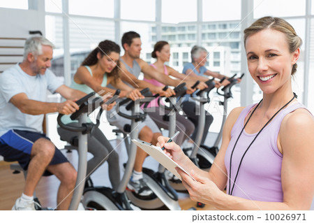 Trainer with people working out at spinning class 10026971