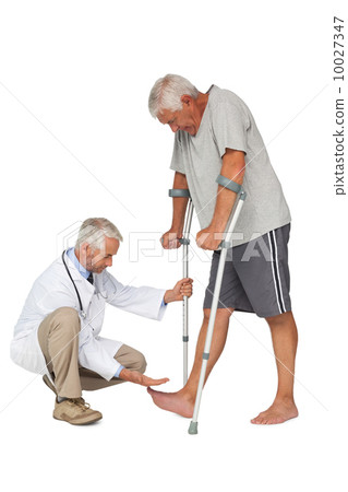 Side view of a doctor with senior man using walker 10027347