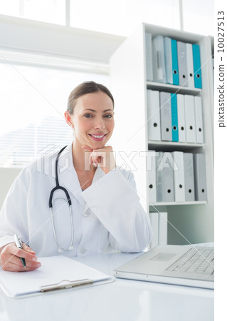 Doctor sitting at desk in clinic Doctor sitting at desk in clinic 10027513