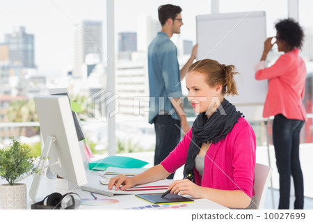 Female artist using graphic tablet with colleagues at office Female artist using graphic tablet with colleagues at office 10027699