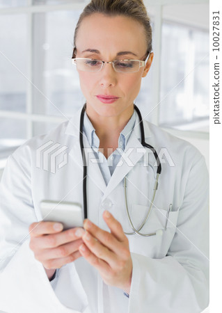 Female doctor reading text message in hospital 10027831