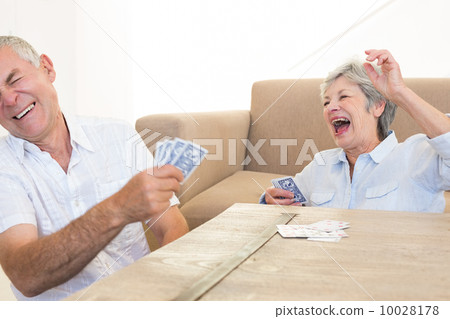 Senior couple sitting on floor playing cards Senior couple sitting on floor playing cards 10028178