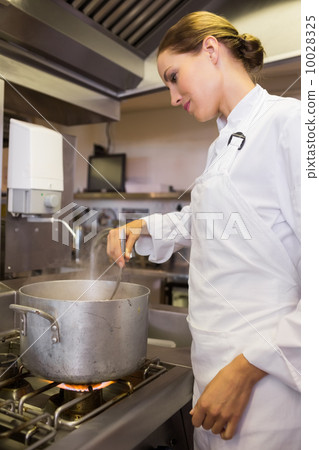Concentrated female cook preparing food in kitchen Concentrated female cook preparing food in kitchen 10028325