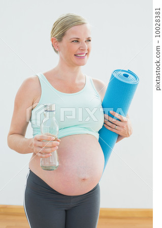 Pregnant woman holding bottle of water and exercise mat Pregnant woman holding bottle of water and exercise mat 10028381