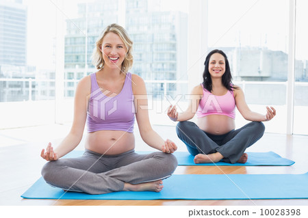Smiling pregnant women in yoga class in lotus pose 10028398