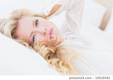 Gorgeous young woman in white shirt smiling at camera lying on b Gorgeous young woman in white shirt smiling at camera lying on b 10028492