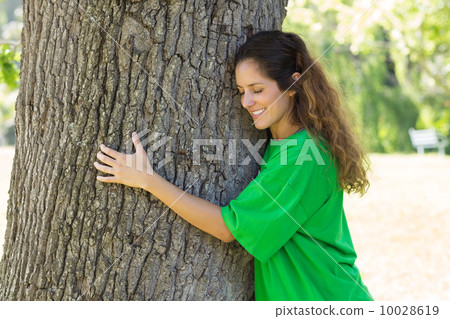 Beautiful environmentalist embracing tree trunk 10028619