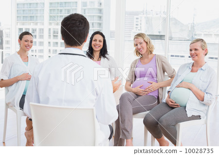 Smiling pregnant women listening to doctor at antenatal class 10028735