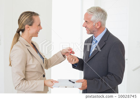 Smiling estate agent giving house key to happy customer Smiling estate agent giving house key to happy customer 10028745