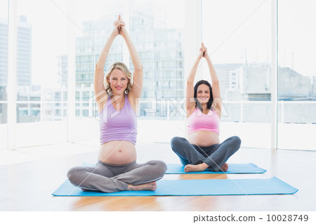 Smiling pregnant women in yoga class sitting in lotus pose 10028749