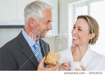 Smiling couple having breakfast in the morning before work Smiling couple having breakfast in the morning before work 10028832