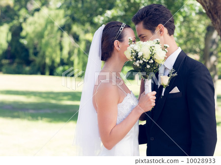 Couple kissing behind bouquet in garden 10028933
