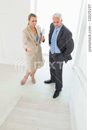Smiling estate agent showing stairs to potential buyer Smiling estate agent showing stairs to potential buyer 10029197