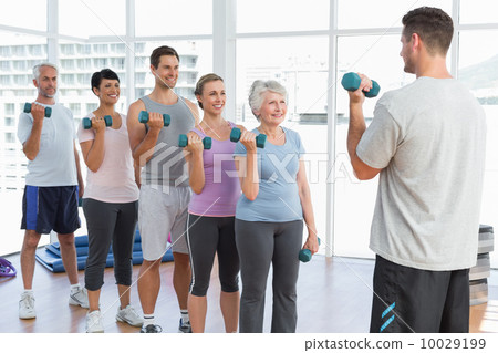 Class exercising with dumbbells in gym Class exercising with dumbbells in gym 10029199