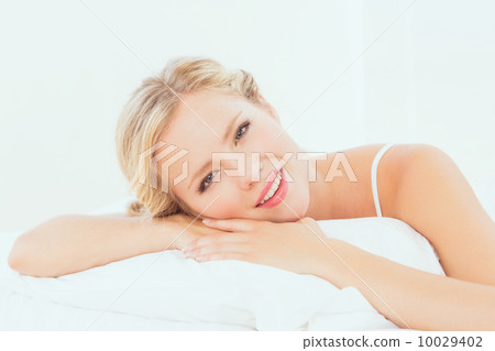Attractive young blonde lying on her bed smiling at camera Attractive young blonde lying on her bed smiling at camera 10029402