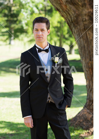 Confident bridegroom in tuxedo at garden 10029611