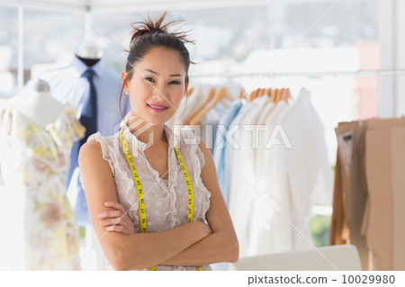 Portrait of a beautiful female fashion designer with rack of clo Portrait of a beautiful female fashion designer with rack of clo 10029980