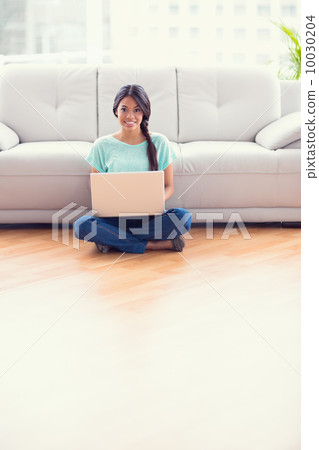 Pretty girl sitting on a floor using laptop smiling at camera Pretty girl sitting on a floor using laptop smiling at camera 10030204
