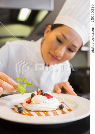 Concentrated female chef garnishing food 10030350