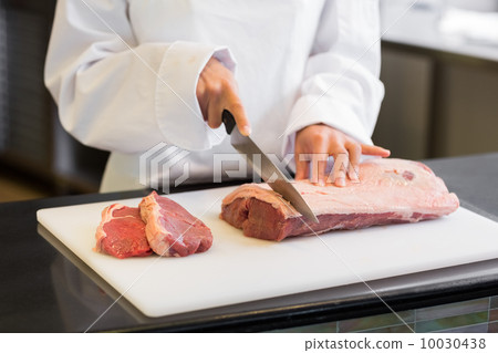 Mid section of hands cutting meat in kitchen 10030438