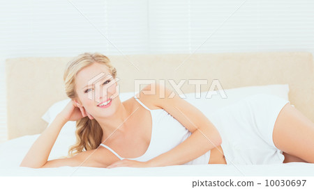 Beautiful blonde lying on her bed smiling at camera Beautiful blonde lying on her bed smiling at camera 10030697