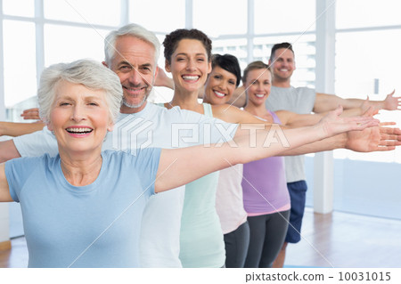 Portrait of fitness class stretching hands in row 10031015
