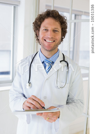 Happy male doctor with clipboard in hospital Happy male doctor with clipboard in hospital 10031386