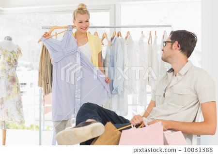 Man with shopping bags while woman selecting a dress Man with shopping bags while woman selecting a dress 10031388