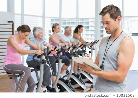 Trainer with people working out at spinning class Trainer with people working out at spinning class 10031502