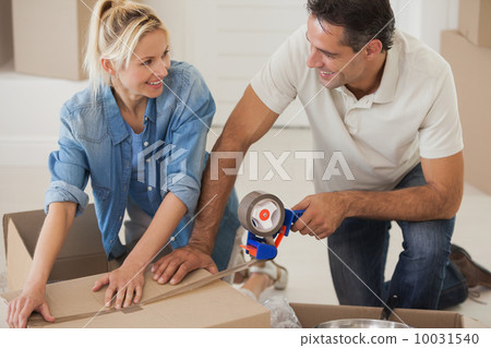 Portrait of a smiling couple packing boxes Portrait of a smiling couple packing boxes 10031540
