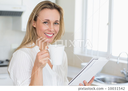 Smiling woman holding mug and newspaper 10031542