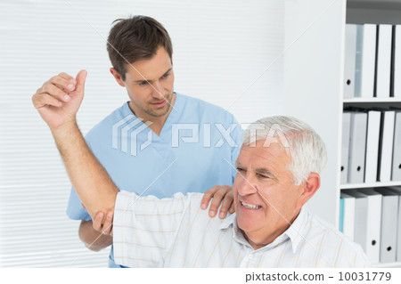 Physiotherapist assisting senior man to stretch his hand 10031779