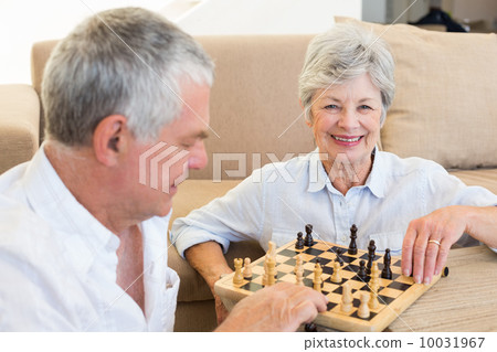 Senior couple sitting on floor playing chess 10031967