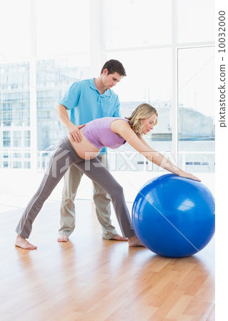 Trainer exercising with pregnant client and exercise ball 10032000