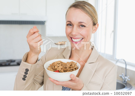 Happy businesswoman eating cereal before work in the morning 10032097
